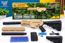 Retail box and unpacked contents of the Happy Kids Hyper Blasters Storm Shooting automatic toy rifle. The display includes a tan and black modular toy gun, a detachable magazine, a rechargeable blue battery, a USB charging cable, interchangeable barrel parts, and a pack of 20 blue EVA soft darts with orange suction cups.